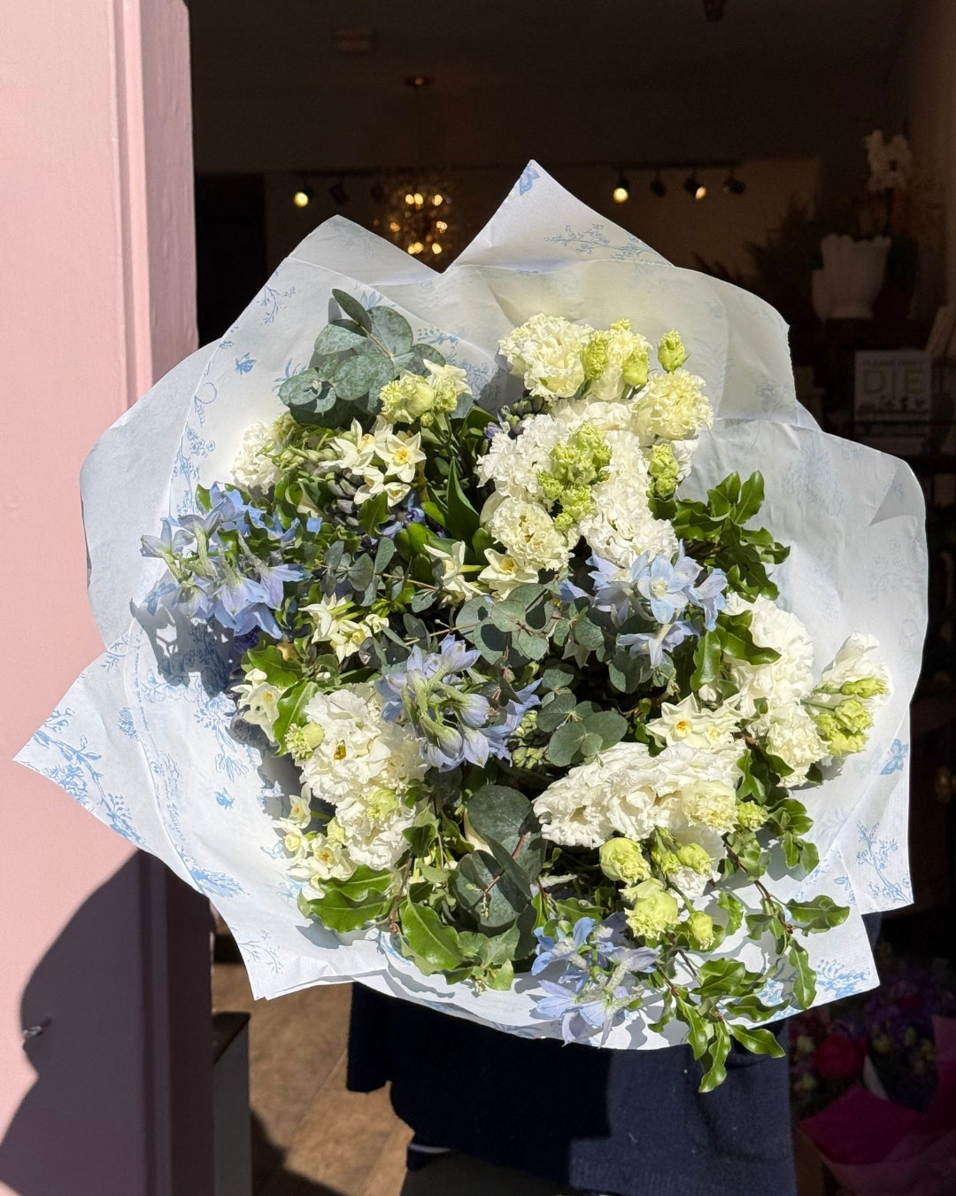 Bouquet of flowers wrapped in white paper against a blurred indoor background