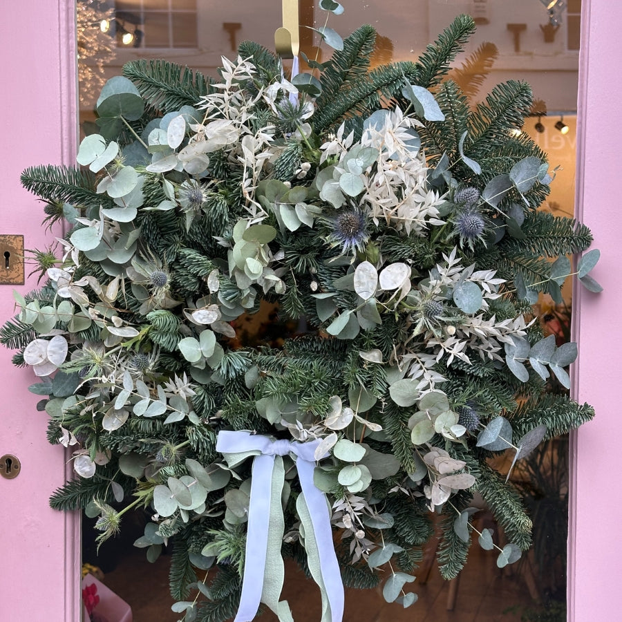 Christmas Wreath, This festive design features Scottish thistle, honesty, bleached white ruscus, and a blend of gunni and cinerea eucalyptus, complemented by rich blue spruce for seasonal depth.