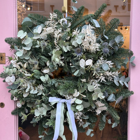 Christmas Wreath, This festive design features Scottish thistle, honesty, bleached white ruscus, and a blend of gunni and cinerea eucalyptus, complemented by rich blue spruce for seasonal depth.